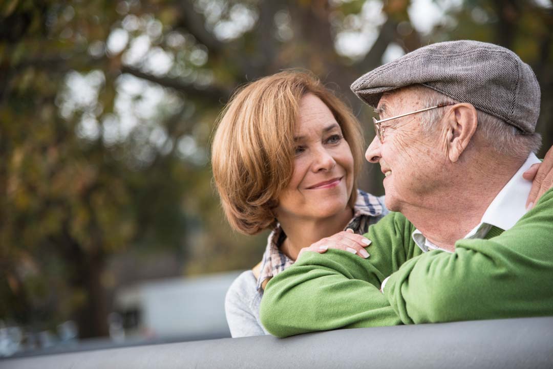 senior man with adult daughter smiling outdoors