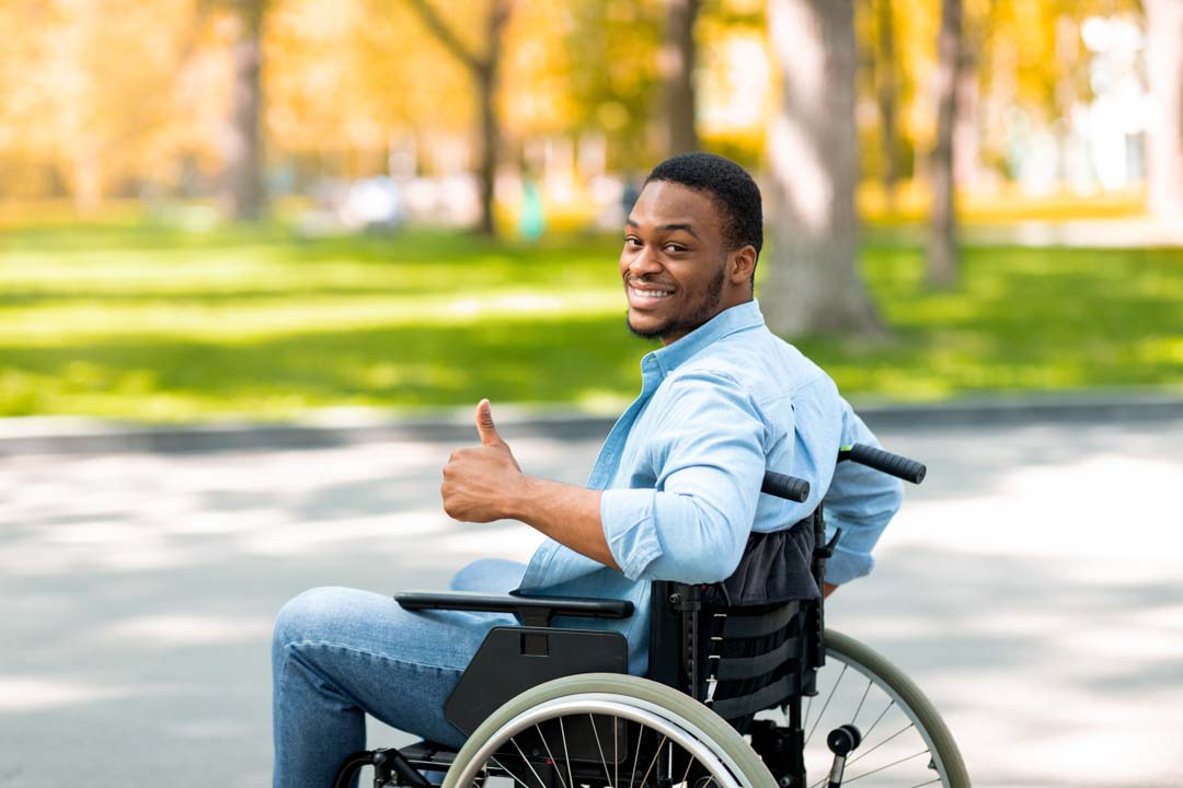 smiling young man in a wheelchair giving a thumbs up