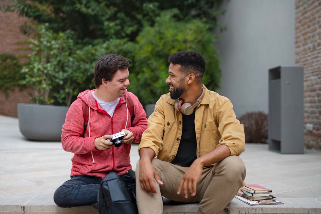 happy young men sitting outside talking