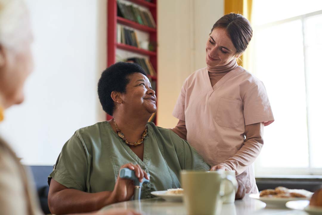 adult day care female nurse chatting with female citizen