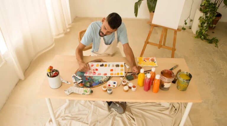 adult painting artwork at a table