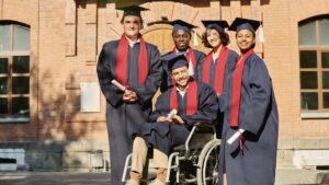 student in wheelchair surrounded by friends graduating high school