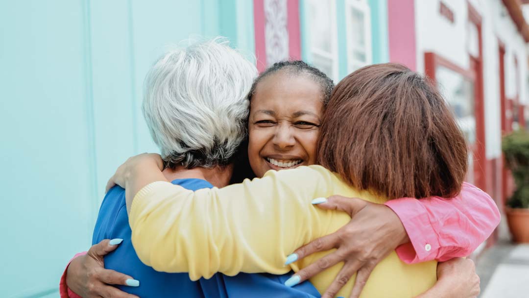 multiracial senior women having fun together hugging