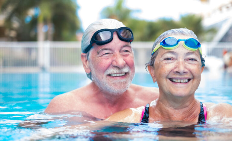 senior couple swimming with goggles